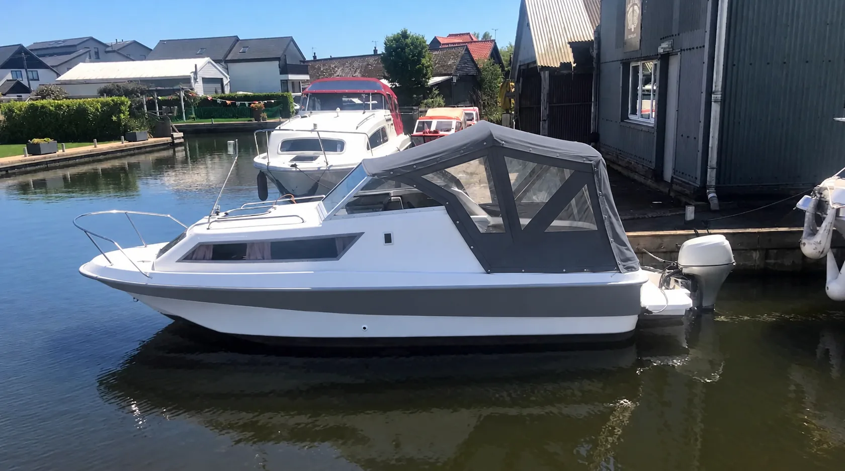 Shetland Family 4 cabin cruiser with grey cockpit canopy moored beside a marina
